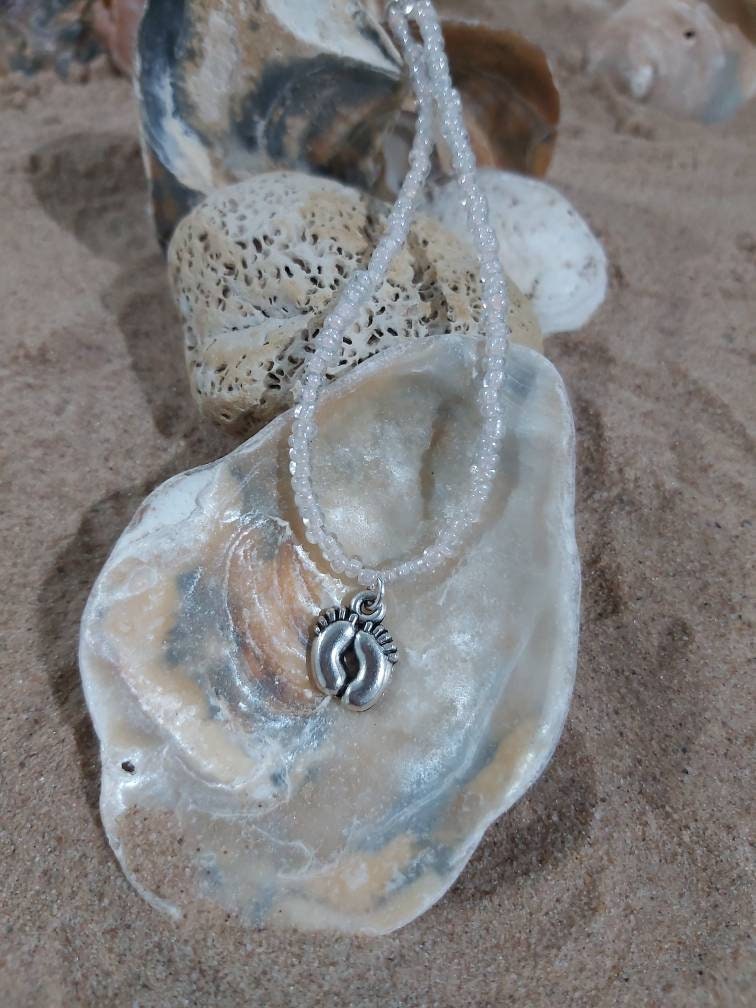 Foot print , feet charm on a dainty seed bead anklet. Anklet is adjustable with a silver plated chain.